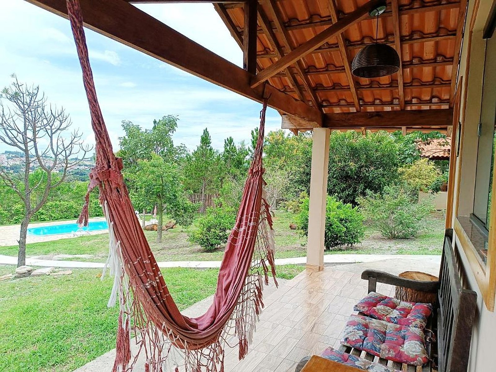 Rede na varanda do chalé, de frente para o jardim e a piscina