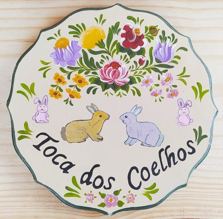 Placa pintada à mão com o nome Toca dos Coelhos, flores e coelhos